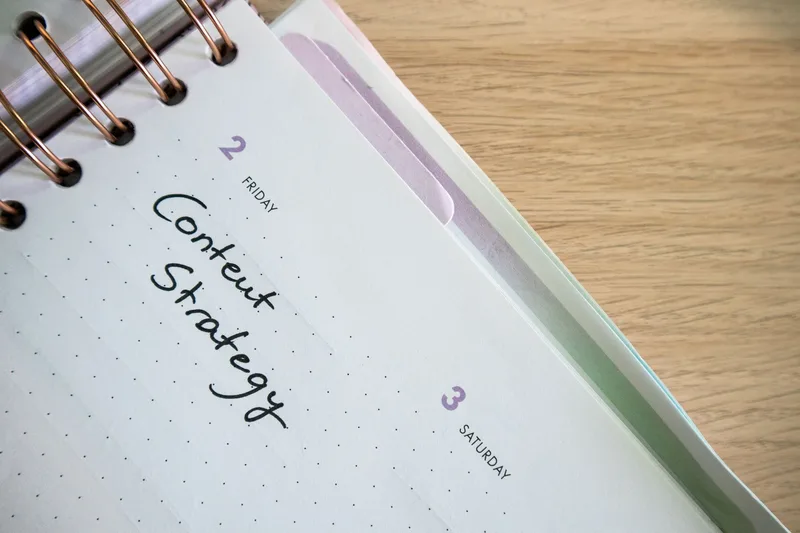 A weekly content planner open on a desk with a laptop, representing a simple scheduling setup for solo creators managing content distribution