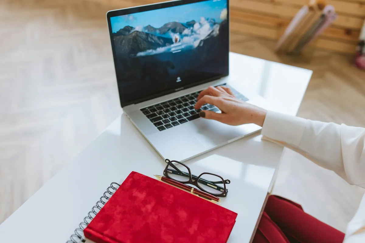 A solo creator working at a minimal desk setup with a planner and laptop, representing a structured content creation workflow without a team