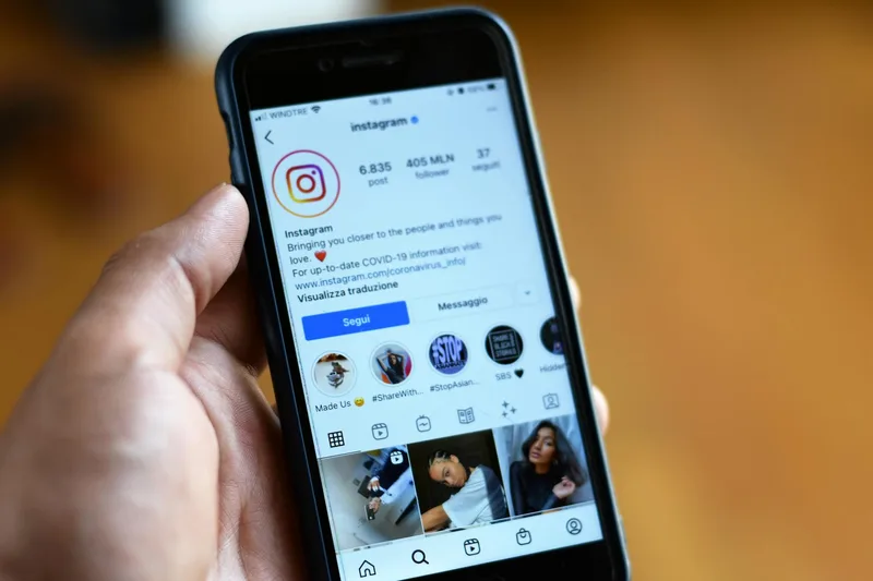 Creator holding a phone showing an Instagram Story with a link sticker pointing to a free lead magnet opt-in page