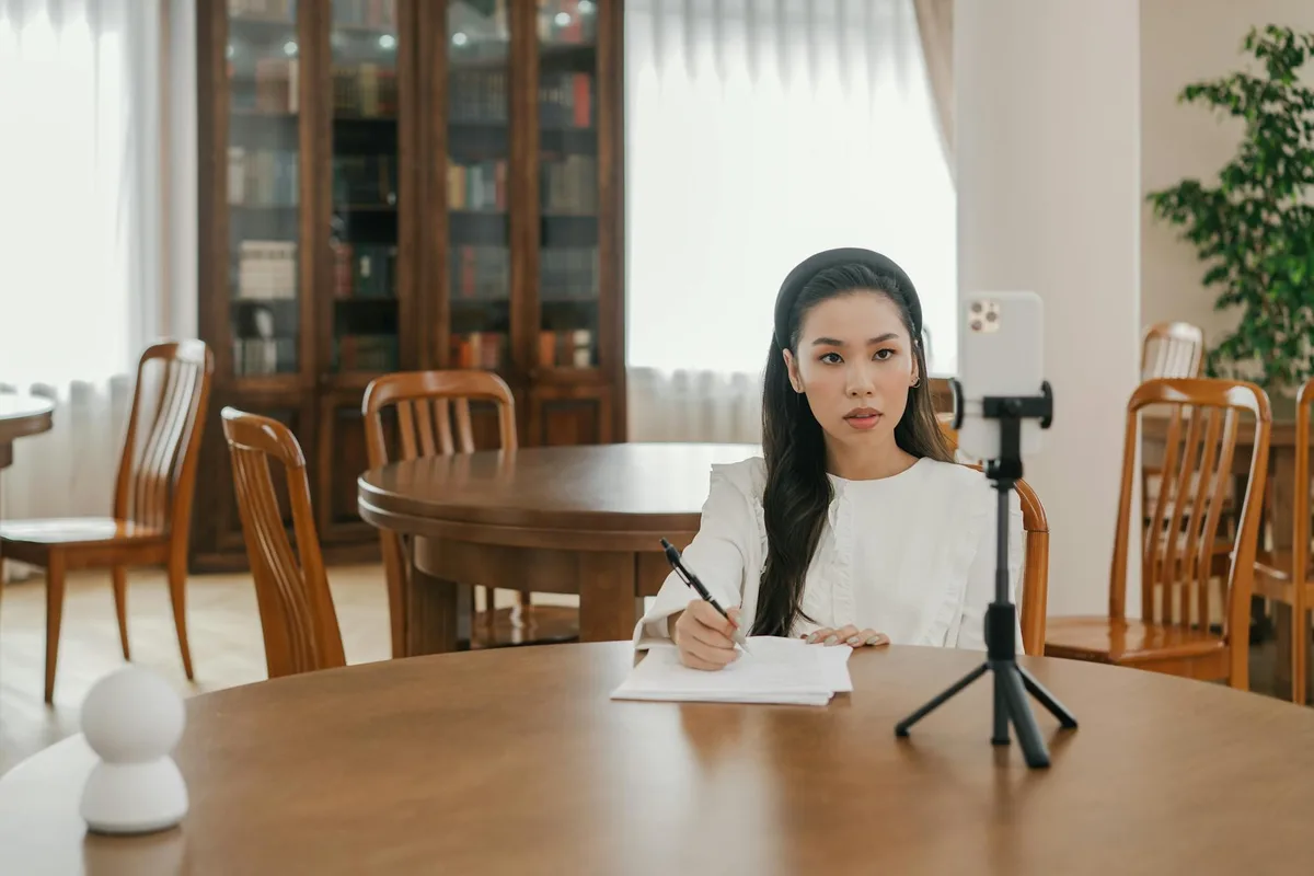 Solo creator filming an Instagram Reel on a phone mounted on a tripod at a bright, minimal home workspace — no heavy production setup