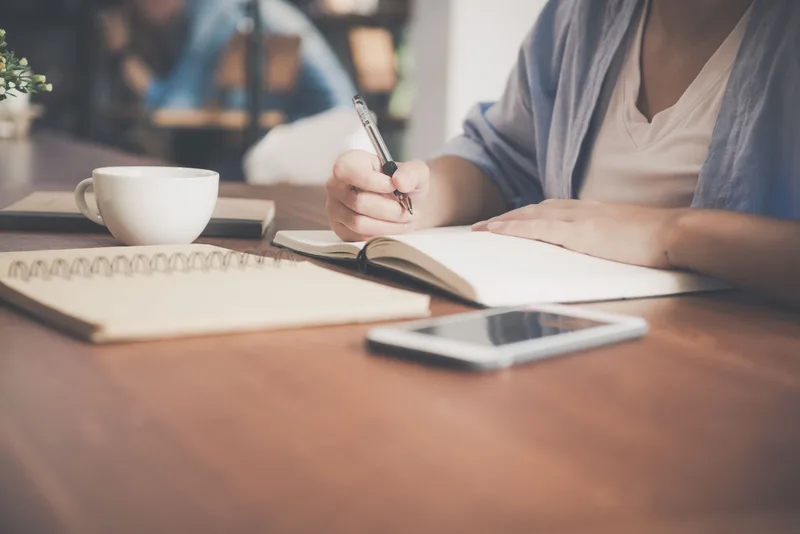 Creator holding pen and reviewing notes while planning authentic story-based LinkedIn content