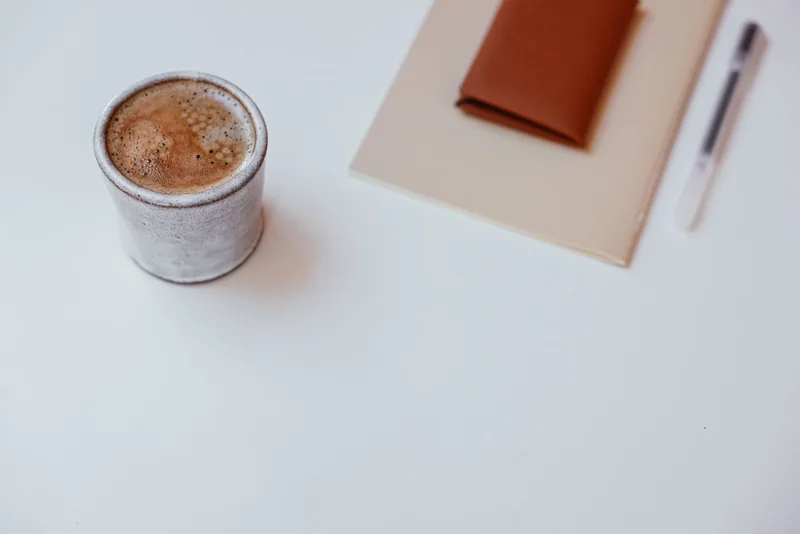 Minimalist desk setup with coffee, notebook and pen representing the simple weekly system for consistent LinkedIn content creation