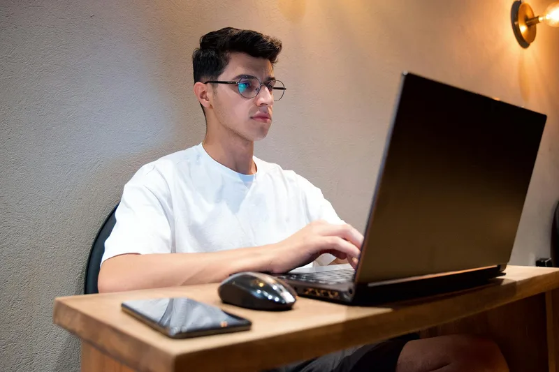 Man in white shirt using laptop at desk with smartphone — TikTok content ideas for freelancers and service providers