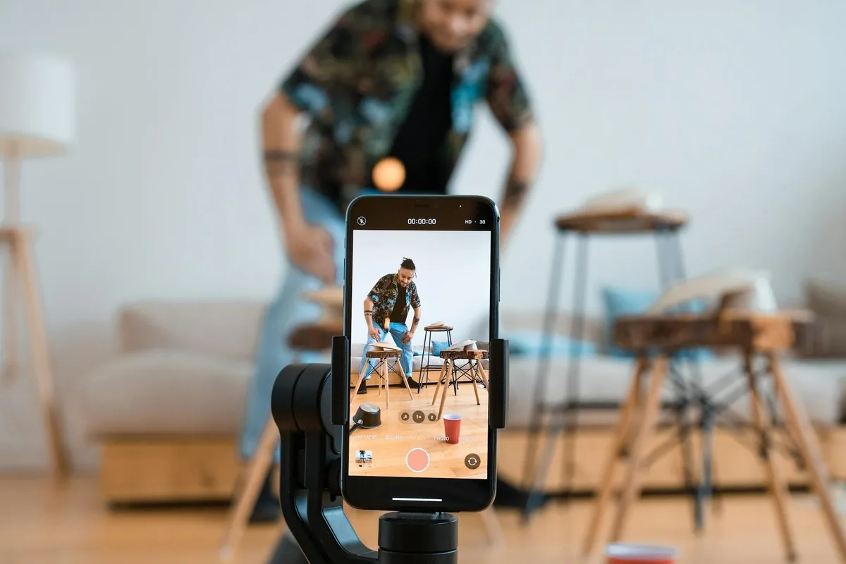 Man recording video content with smartphone on a tripod in a cozy living room — TikTok content ideas for solo creators