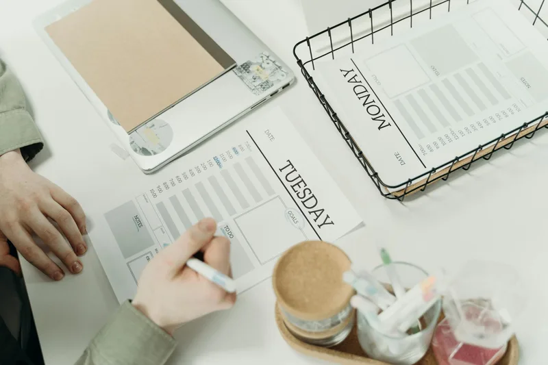 A professional organizing their week with a schedule planner in an office setting