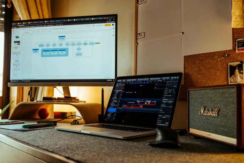 Content creator working at a dual-monitor setup, planning thumbnail designs for upcoming videos
