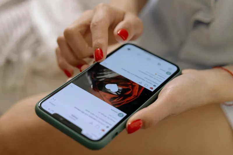 Person scrolling a social media feed on a smartphone, representing the mobile thumbnail viewing experience