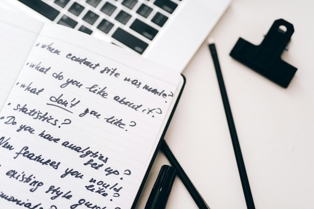 Solo creator at desk with laptop and notebook, planning a YouTube channel concept based on business goals