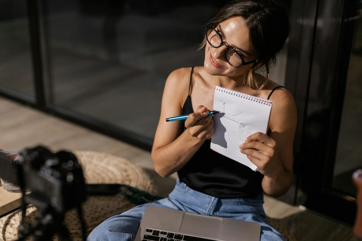 Creator recording a tutorial video with notes on a whiteboard behind them — illustrating a channel concept built around teaching a skill